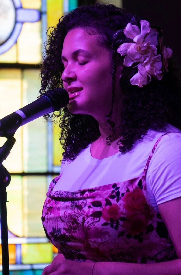 Woman singing with flowers in her hair by a microphone.