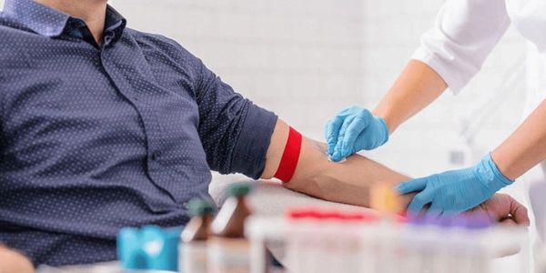 A healthcare worker prepares to draw blood from a patient's arm.