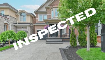 A well-maintained brick house with a clean driveway and lush greenery, marked 'INSPECTED.'