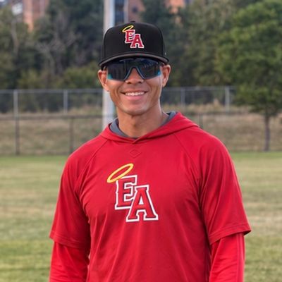 Baseball player smiling on field in red EA jersey.