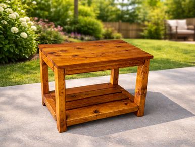 Sturdy wooden outdoor table on a concrete patio with garden background.