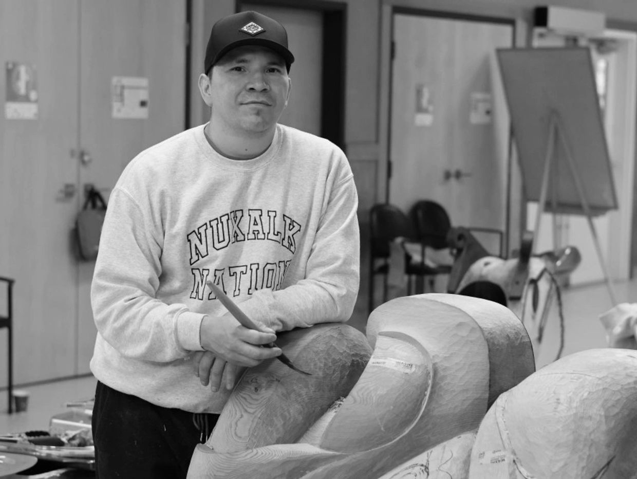 Man carving wood with brush in art studio.