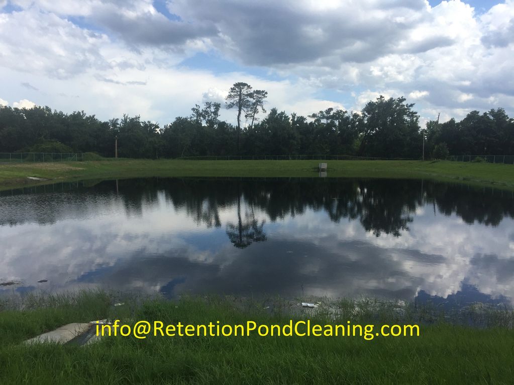 A calm retention pond reflecting trees and cloudy sky, with an email address for pond cleaning services.