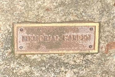 Rusty plaque reading 'MEMORIAL GARDEN' on a stone surface.