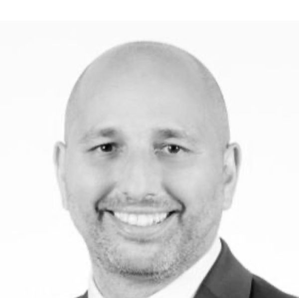 Black and white portrait of a smiling bald man in a suit.