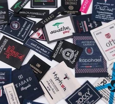 A collection of various clothing brand labels and tags scattered on a surface.