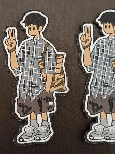Three identical cartoon patches of a boy making a peace sign on a dark surface.