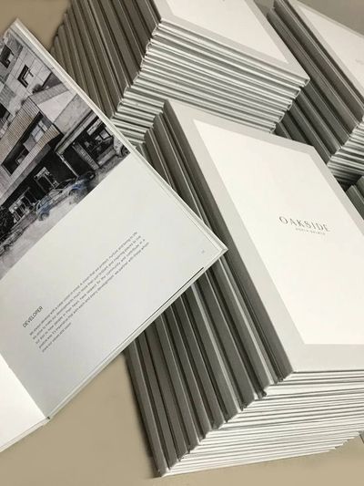 Stacks of professionally bound brochures with clean, white covers and high-quality prints