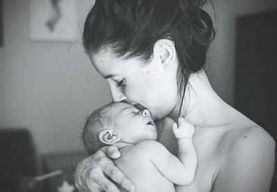 Home birth mom kissing the top of her newborn baby's head