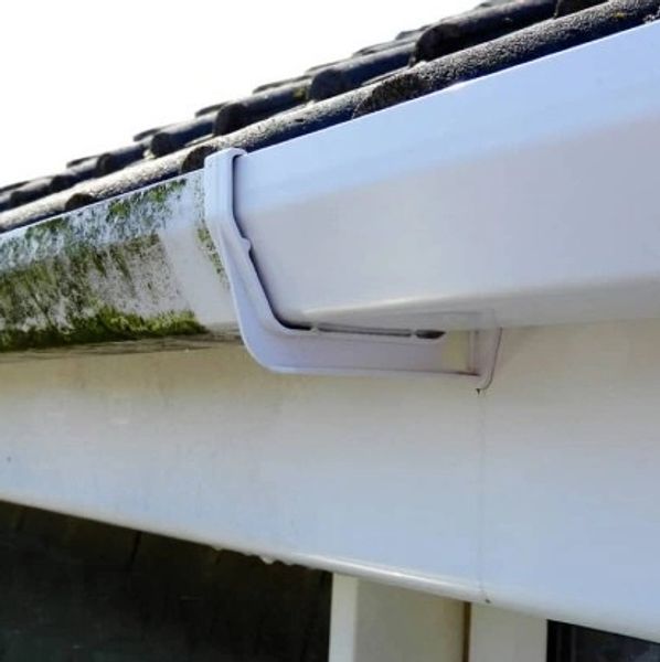 Side-by-side comparison of a dirty and clean gutter on a roof that as UPVC washing