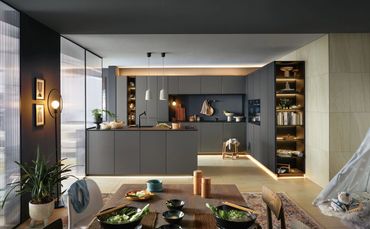 Modern kitchen with dark cabinetry, island, and cozy dining area with bowls and chopsticks.