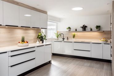 Modern white kitchen with wooden accents and plants.