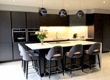 Modern kitchen with black cabinetry, white island, and pendant lights.