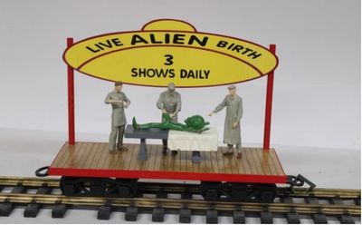 Model train display with live alien birth sign and figures.