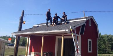 Red Farmstand with 3 workers on the new roof.  RKC gives back to the community