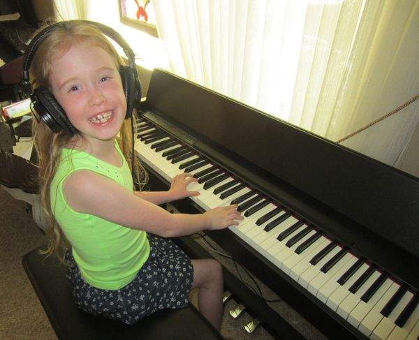Young girl playing a digital piano and learning to play music
