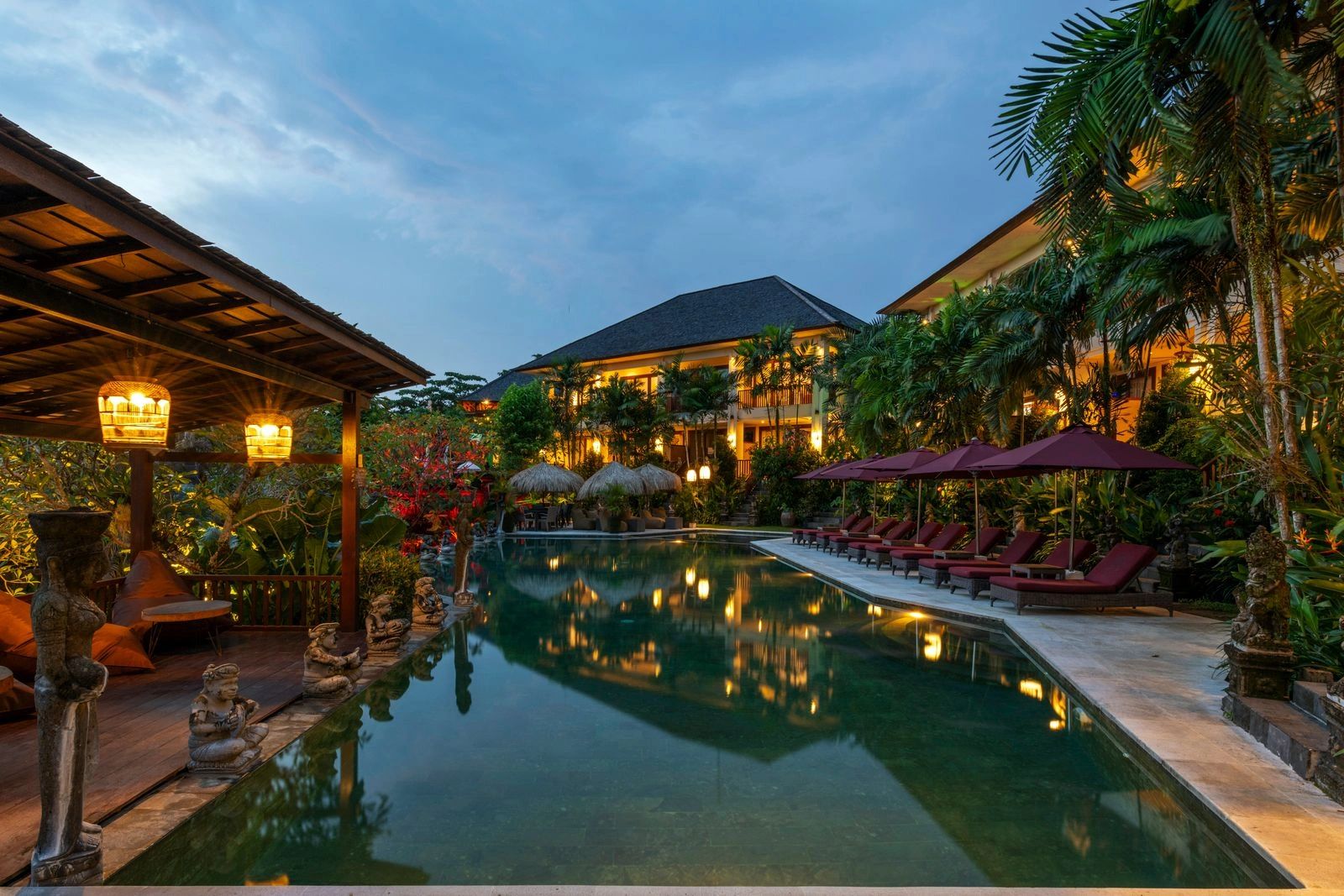Luxurious tropical resort pool at dusk with cozy seating.