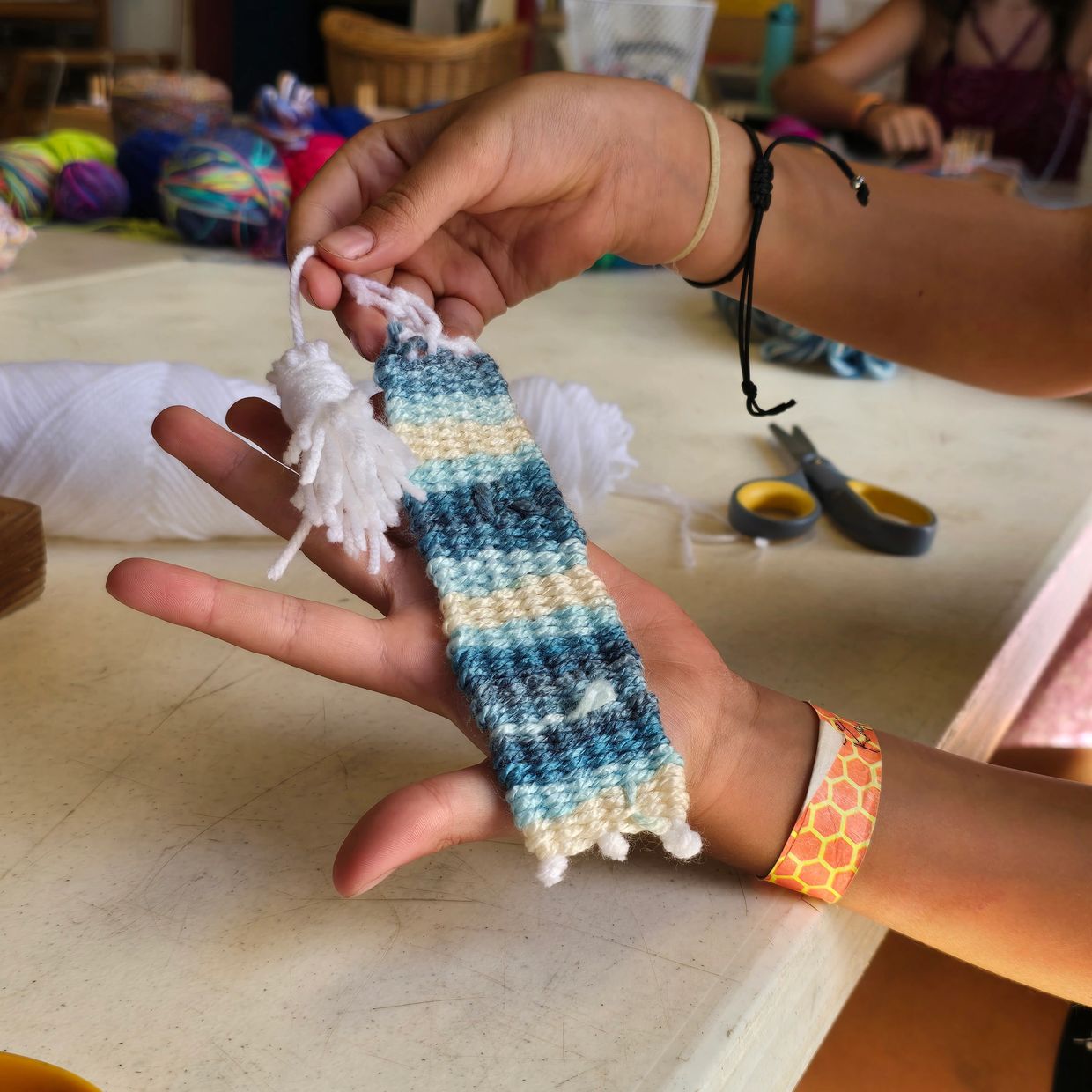 Hand holding a woven bookmark with blue and white stripes.