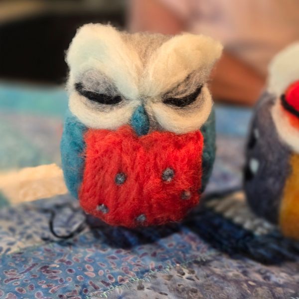Colorful felted owl figurine with prominent eyes and patterned body.