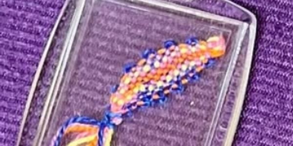 Colorful handmade woven bracelet on a purple fabric.