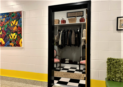 a walk in coat closet with black and white tile floor