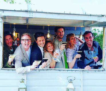 Wedding guests enjoying cocktails in our horsebox bar at gay wedding