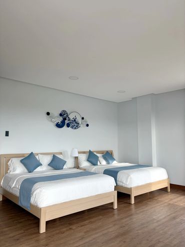 Modern bedroom with two beds, blue accents, and wooden flooring.