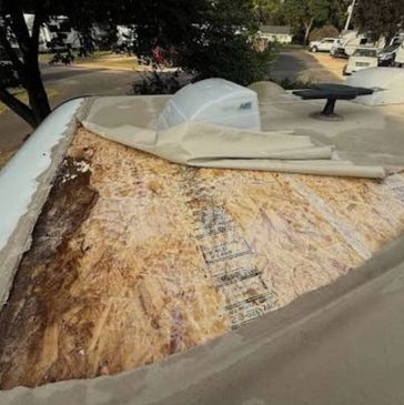 Damaged and peeled roof surface revealing plywood underlayer.