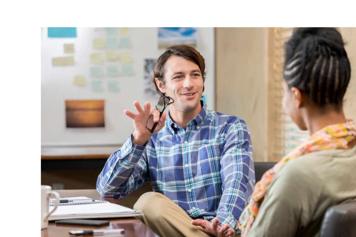 Man holding glasses while talking to a woman.