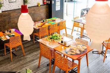 Bright restaurant interior with orange chairs and colorful tables.