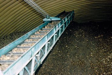 Conveyor belt moving grain in metal shed