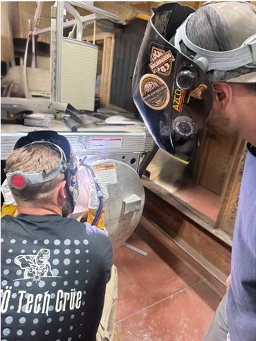 Two experienced marine technicians performing aluminum welding on a pontoon boat component using TIG