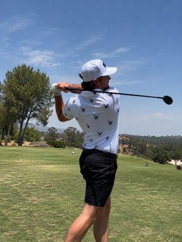 Golfer swinging on a sunny golf course.