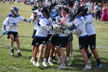 Youth lacrosse team celebrating a victory on the field.