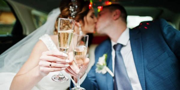 Newly married couple drinking champagne in the limousine on their wedding day.
