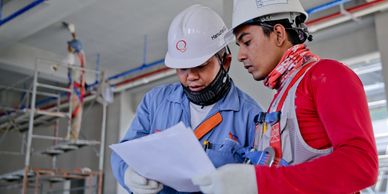 Two persons at an industrial site looking at safety checklists to conduct an audit.