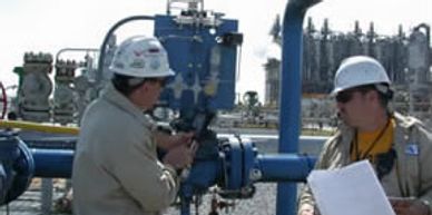 Photo of two men conducting a safety audit of piping systems at an industrial site.