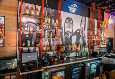 Interior view of a colorful bar with liquor bottles and taps.