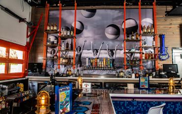 Modern bar interior with artistic decor and vibrant lighting.