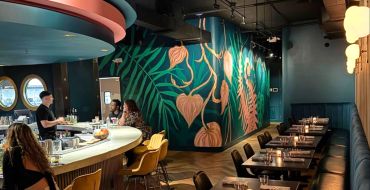 Stylish bar with artistic green and orange wall mural.