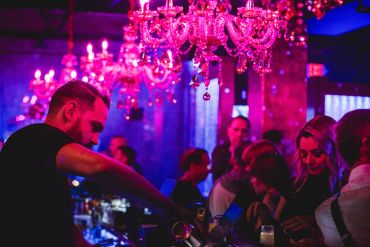 People socializing in a nightclub with pink chandeliers.