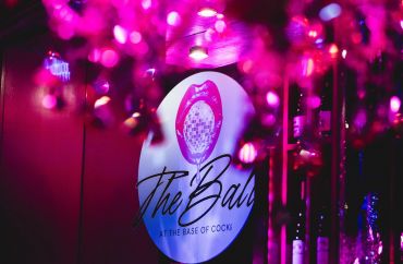 A neon-lit sign with 'The Ball' and a pink decorative light.