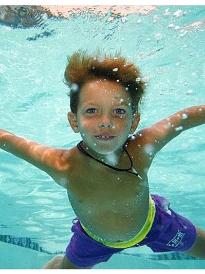 Boy swimming underwater with arms outstretched.