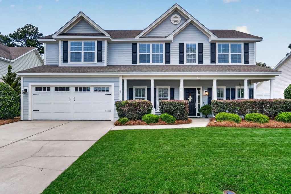 Two-story suburban house with a large driveway and manicured lawn.