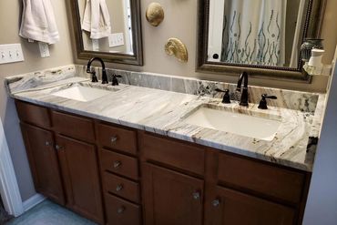 Double sink bathroom vanity with marble countertop and wooden cabinets.