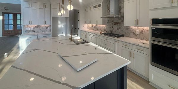 Modern kitchen with white marble countertops and gold fixtures.