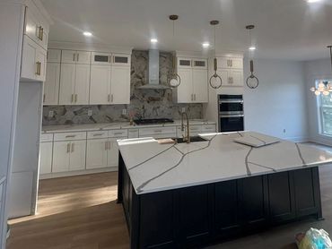 Modern kitchen with white cabinets, marble countertops, and pendant lighting.