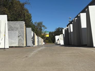 Stacks of large stone slabs arranged outdoors under a clear blue sky.