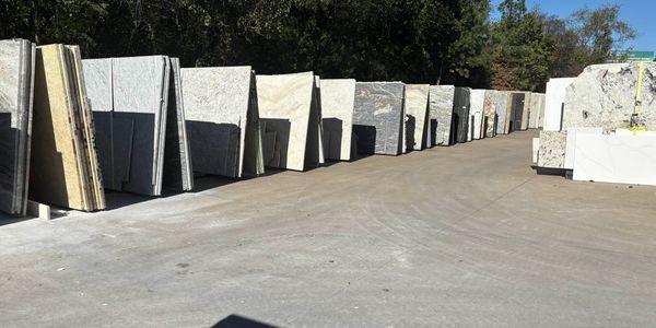 Rows of large stone slabs displayed outdoors on a sunny day.