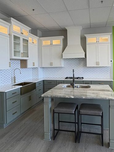 Modern kitchen showroom with gray and white cabinetry and marble island.